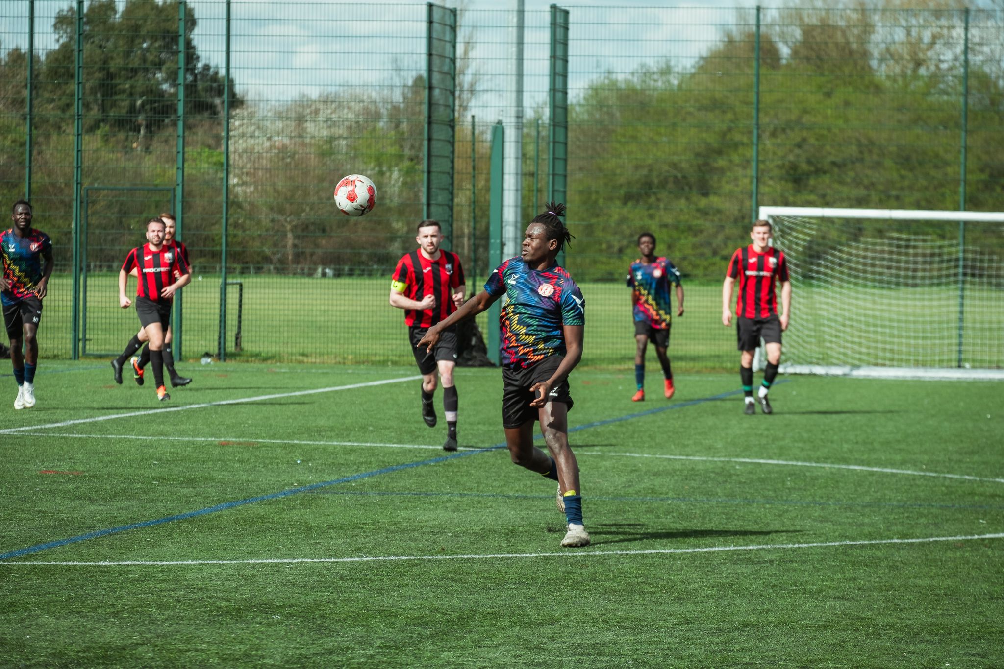 Changing Lives FC Refugee Football Player dribbling in the Klabu Teamwear Multisport Shirt