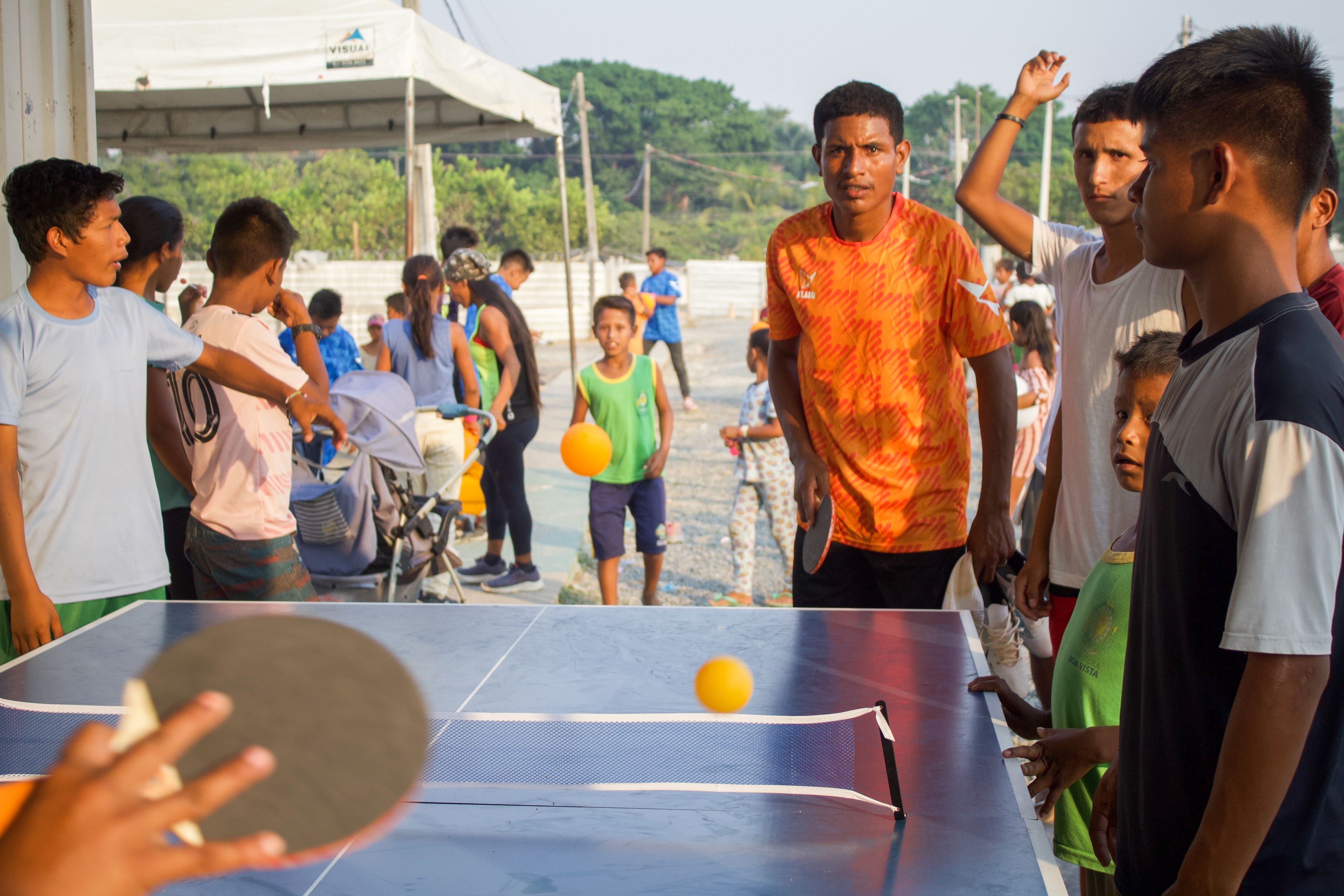 kids surrounded playing table tennis with group