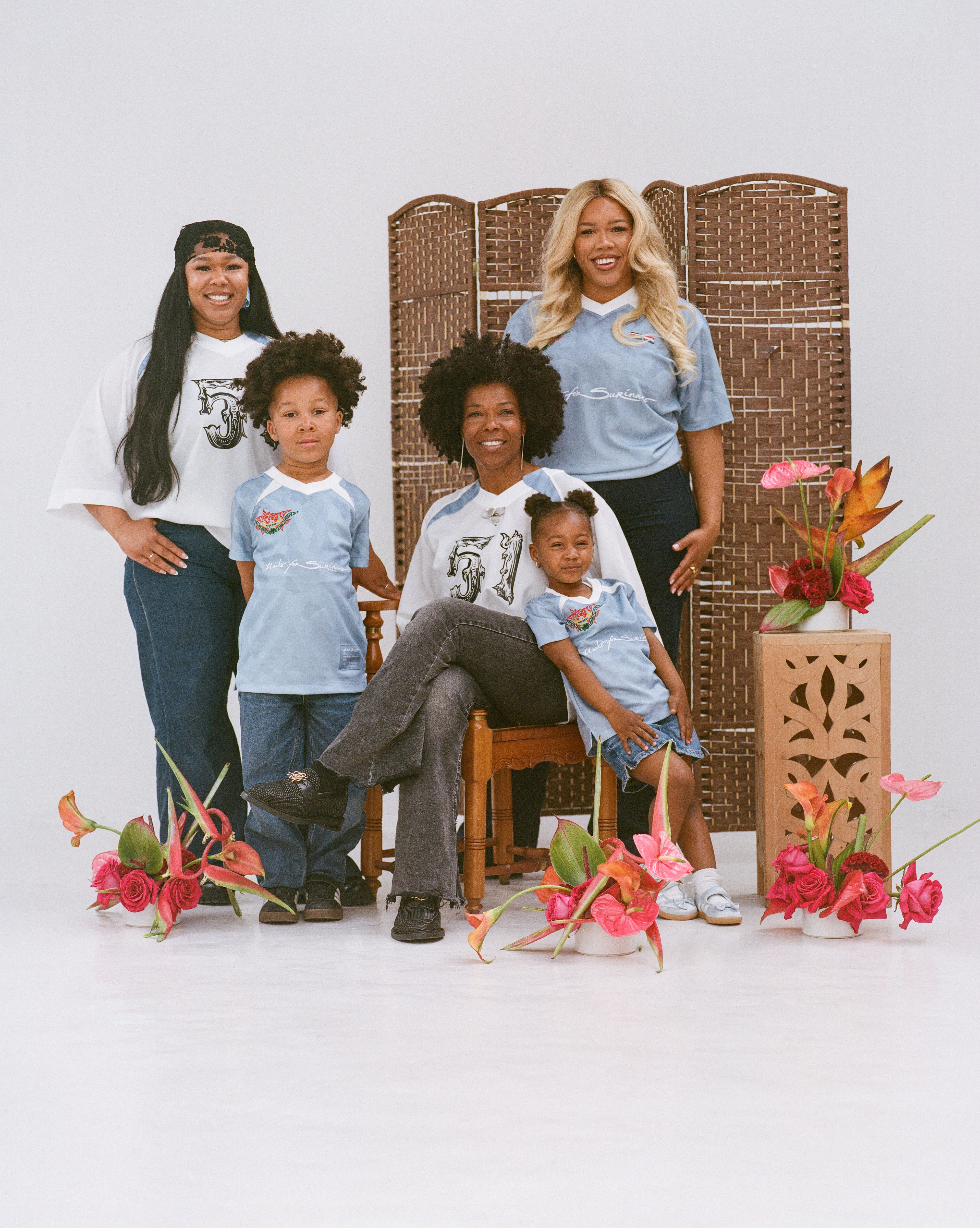 Family of Surinamese decent posing together wearing limited edition Keti Koti Jerseys with flowers surrounding them.