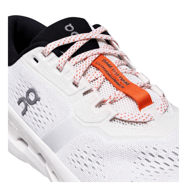 White athletic shoe with black and orange details, mesh upper, and logo on the side. Visible text on lace tab reads "Cloudrunner Day to Day."