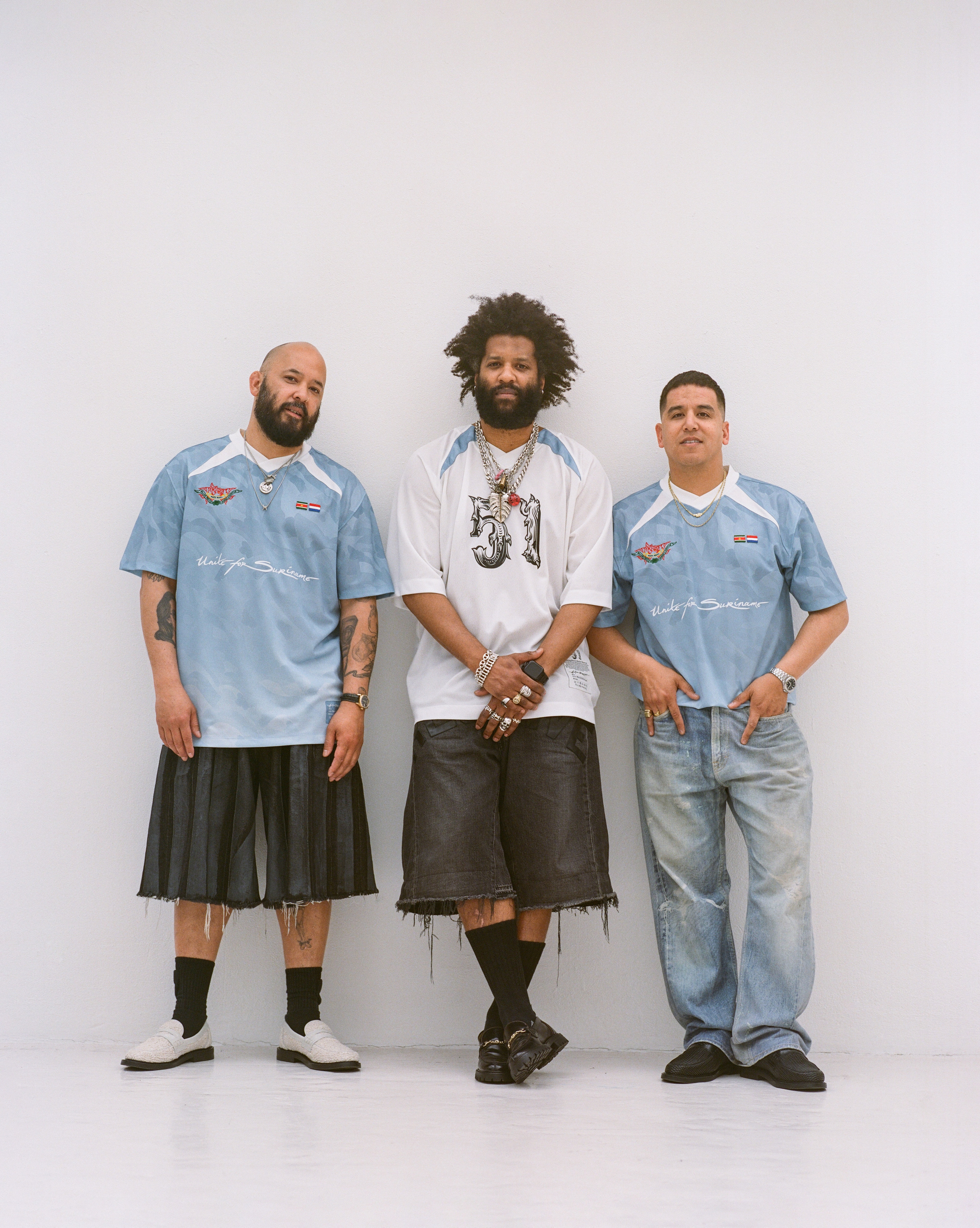 Three individuals of Surinamese descent posing with a limited edition Keti Koti jerseys